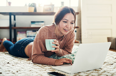 Buy stock photo Full length shot of an attractive young woman lying on the floor and using her laptop at home