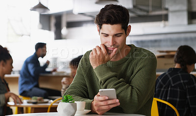Buy stock photo Shot of a handsome young man using a cellphone in a cafe