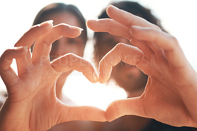 Buy stock photo Cropped shot of an unrecognizable couple making a heart shape with their hands while standing on the beach