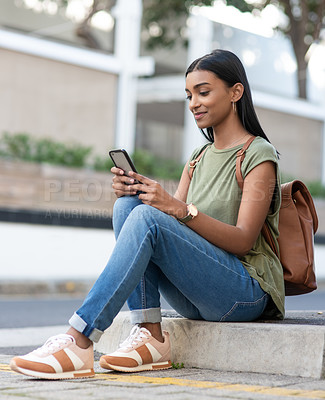 Buy stock photo Indian woman, phone and chat in outdoor with sitting for online conversation, social media and backpack. Female student, mobile and bag in town for web search, internet connection and reading text