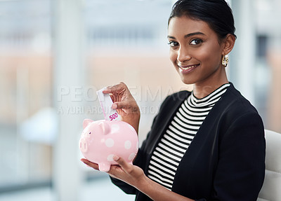 Buy stock photo Portrait of an attractive young businesswoman putting money inside her piggy bank at work