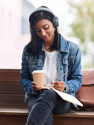 Buy stock photo Cropped shot of a young woman making notes while sitting outdoors