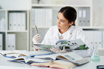 Buy stock photo Shot of a young scientist reading a book while working with plant samples in a lab
