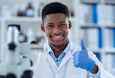 Buy stock photo Portrait of a cheerful young male scientist wearing protective gloves while showing thumbs up inside of a laboratory during the day