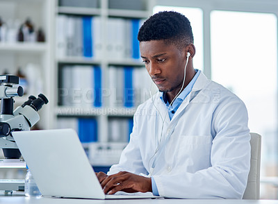 Buy stock photo Science, man and laptop in lab with typing for medical research, microscopic experiment or DNA testing with earphones. Scientist, african expert or serious for gene editing or healthcare breakthrough