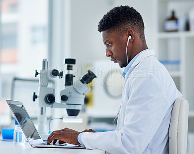 Buy stock photo Scientist, man and laptop in lab with research for medical study, microscopic experiment or DNA testing with earphones. Science, african expert and serious for gene editing or healthcare breakthrough