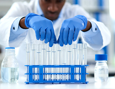 Buy stock photo Cropped shot of a focused young male scientist packing test tubes on top of a small rack inside of an laboratory during the day