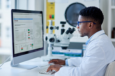 Buy stock photo Cropped shot of a focused young male scientist working on his computer while being seated inside of a laboratory during the day