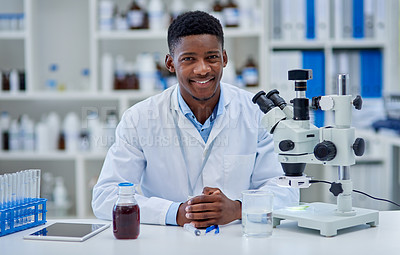 Buy stock photo Portrait of a cheerful young male scientist standing at his desk inside of a laboratory during the day