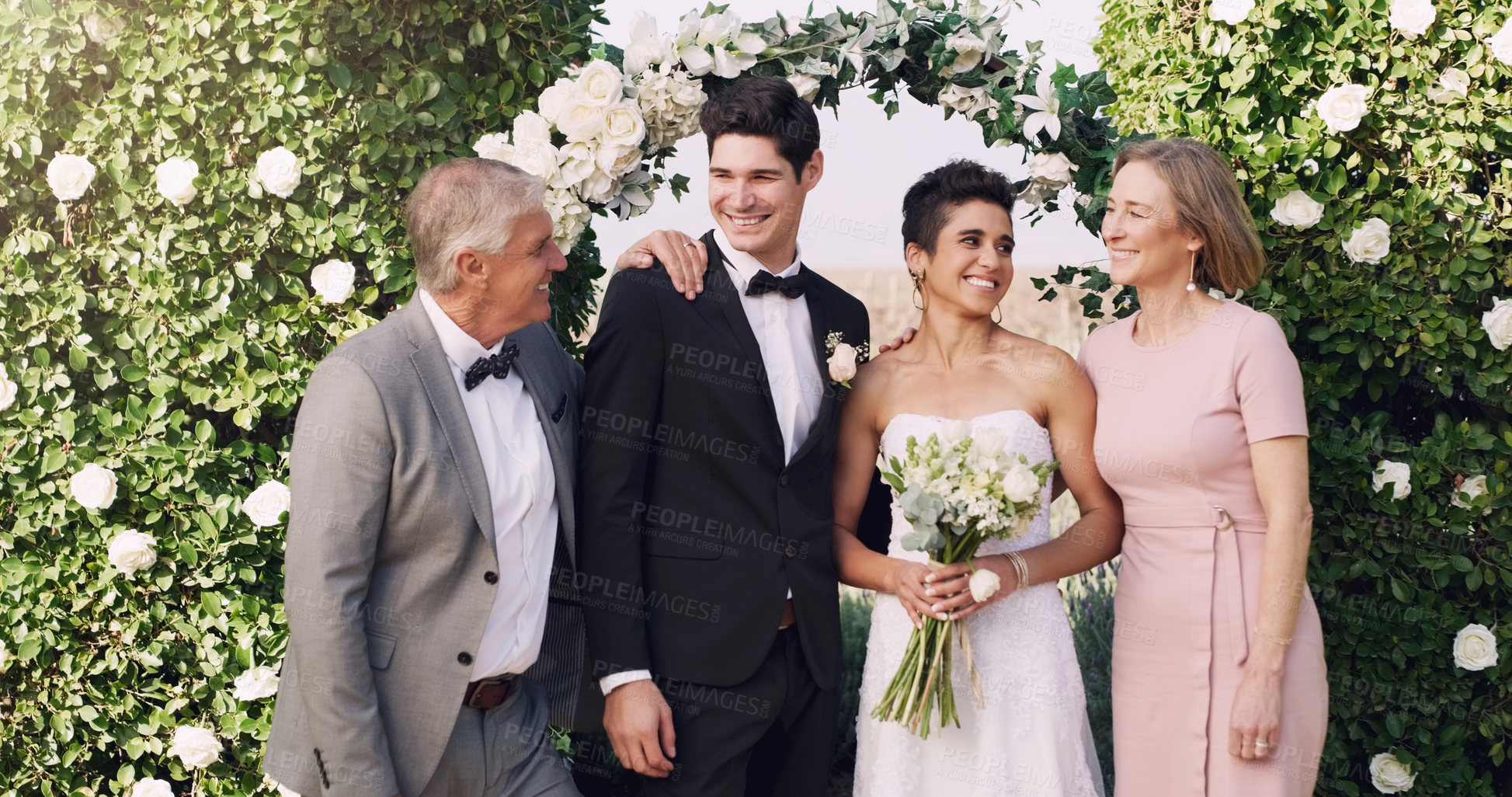 Buy stock photo Cropped shot of an affectionate young newlywed couple standing with their parents on their wedding day