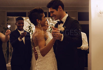 Buy stock photo Cropped shot of an affectionate young newlywed couple dancing while their guests are holding up sparklers at their wedding reception