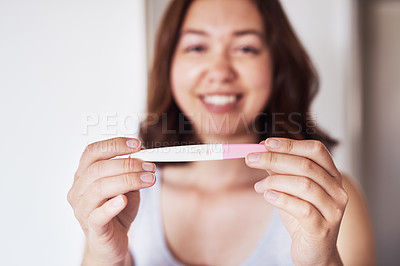 Buy stock photo Cropped shot of a young woman holding up a pregnancy test at home