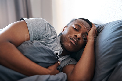 Buy stock photo Cropped shot of a handsome young man lying in bed and feeling depressed while home alone