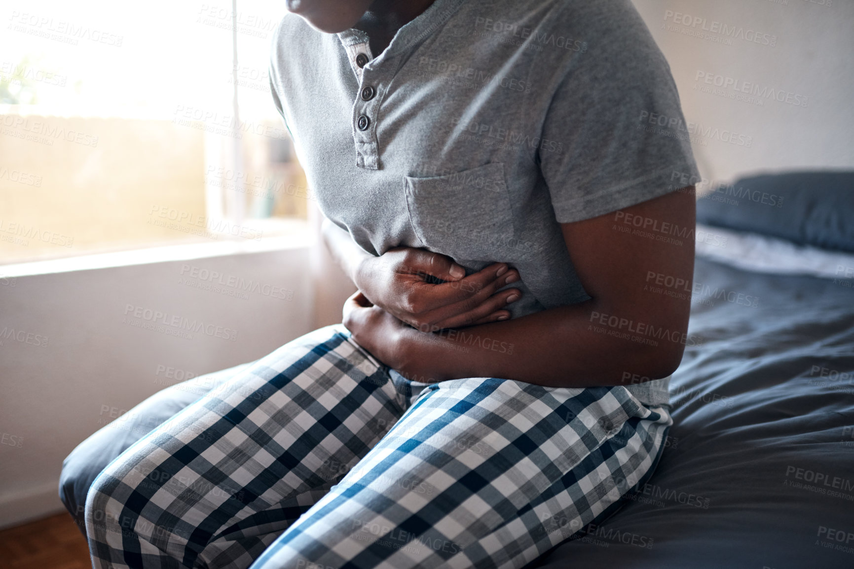 Buy stock photo Man, stomach ache and hands holding belly in a bedroom in a home at morning. African male person, sick and indigestion pain in a house on a bed feeling hurt with abdomen cramp and ibs problem