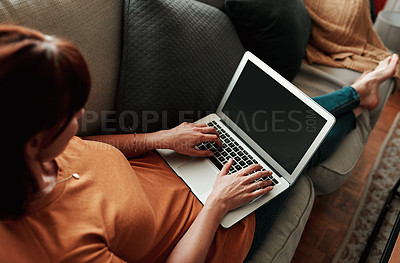 Buy stock photo shot of an unrecognizable woman using her laptop at home