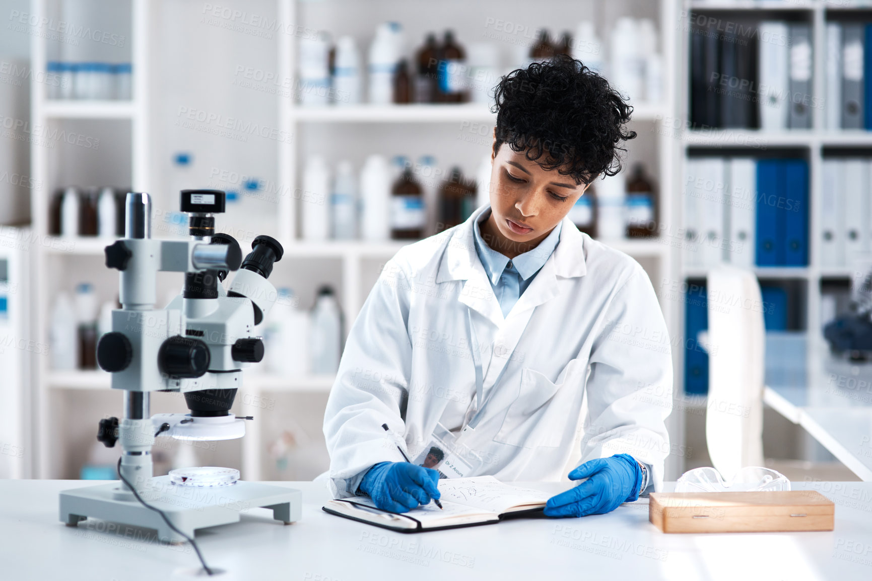 Buy stock photo Shot of a young scientist writing  notes while working in a lab