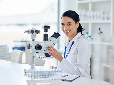 Buy stock photo Portrait of a young scientist using a microscope in a laboratory