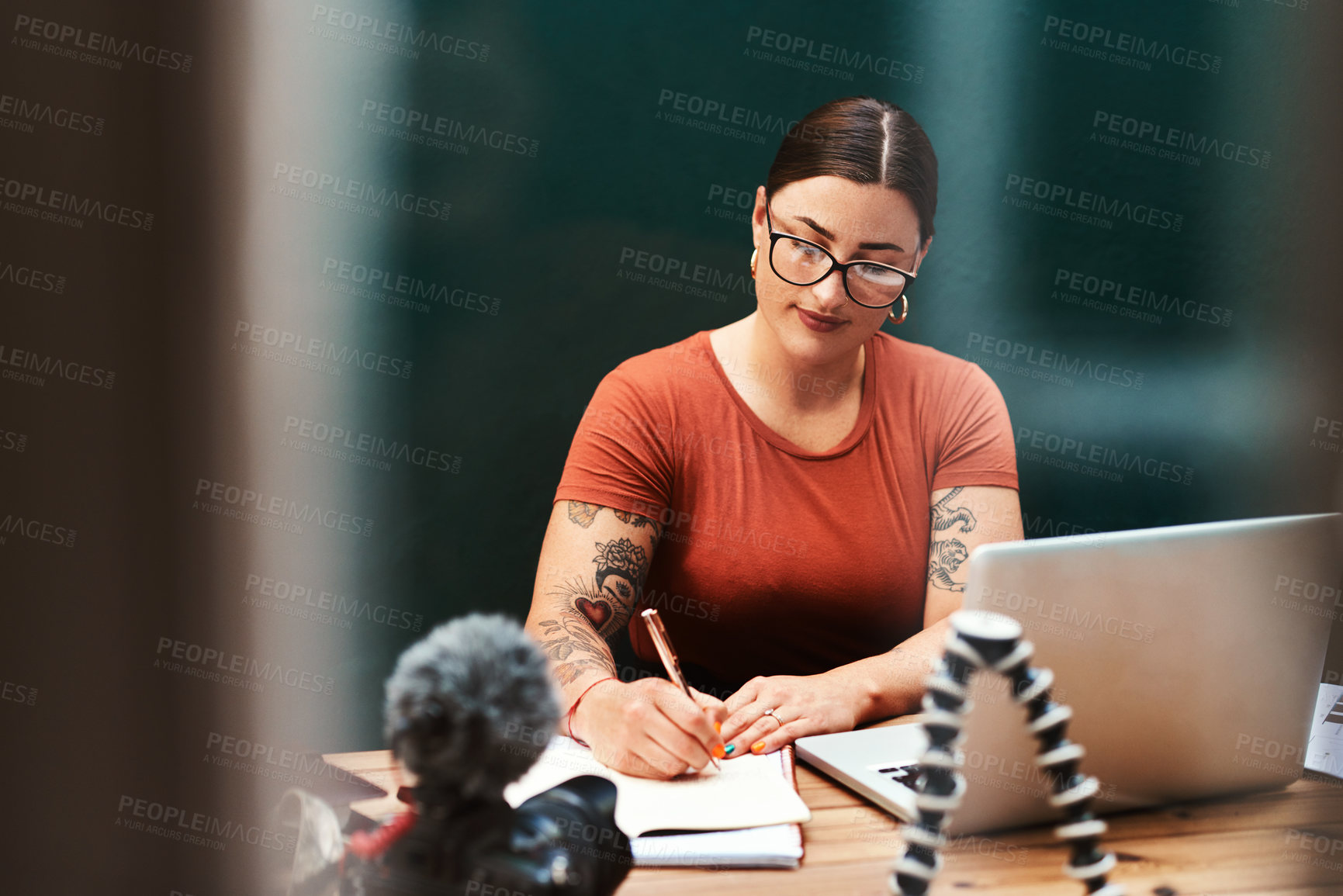 Buy stock photo Cropped shot of an attractive young businesswoman sitting alone at her desk and writing in her notebook