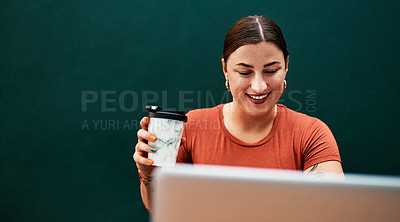 Buy stock photo Cropped shot of an attractive young businesswoman sitting alone and using her laptop while holding a cup of coffee