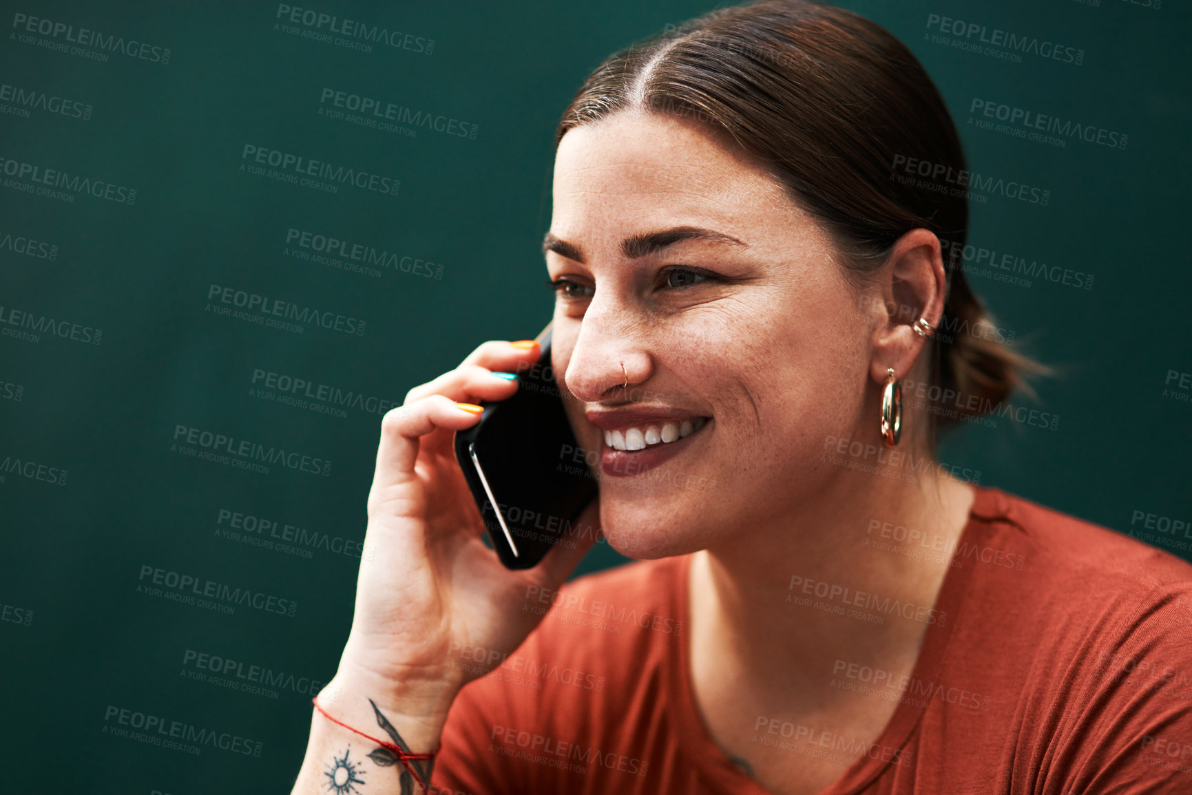 Buy stock photo Cropped shot of an attractive young businesswoman sitting alone against a green background and using her cellphone