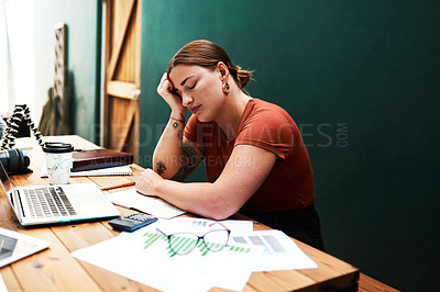 Buy stock photo Cropped shot of an attractive young businesswoman sitting alone at her desk and suffering from a headache