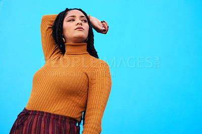 Buy stock photo Cropped shot of a beautiful young woman posing against a blue wall