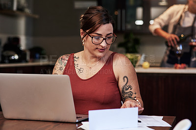 Buy stock photo Cropped shot of a cheerful young woman working on a laptop and doing paperwork while being seated at a table at home