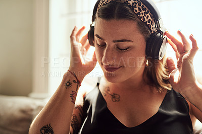 Buy stock photo Shot of a young woman using headphones on the sofa at home