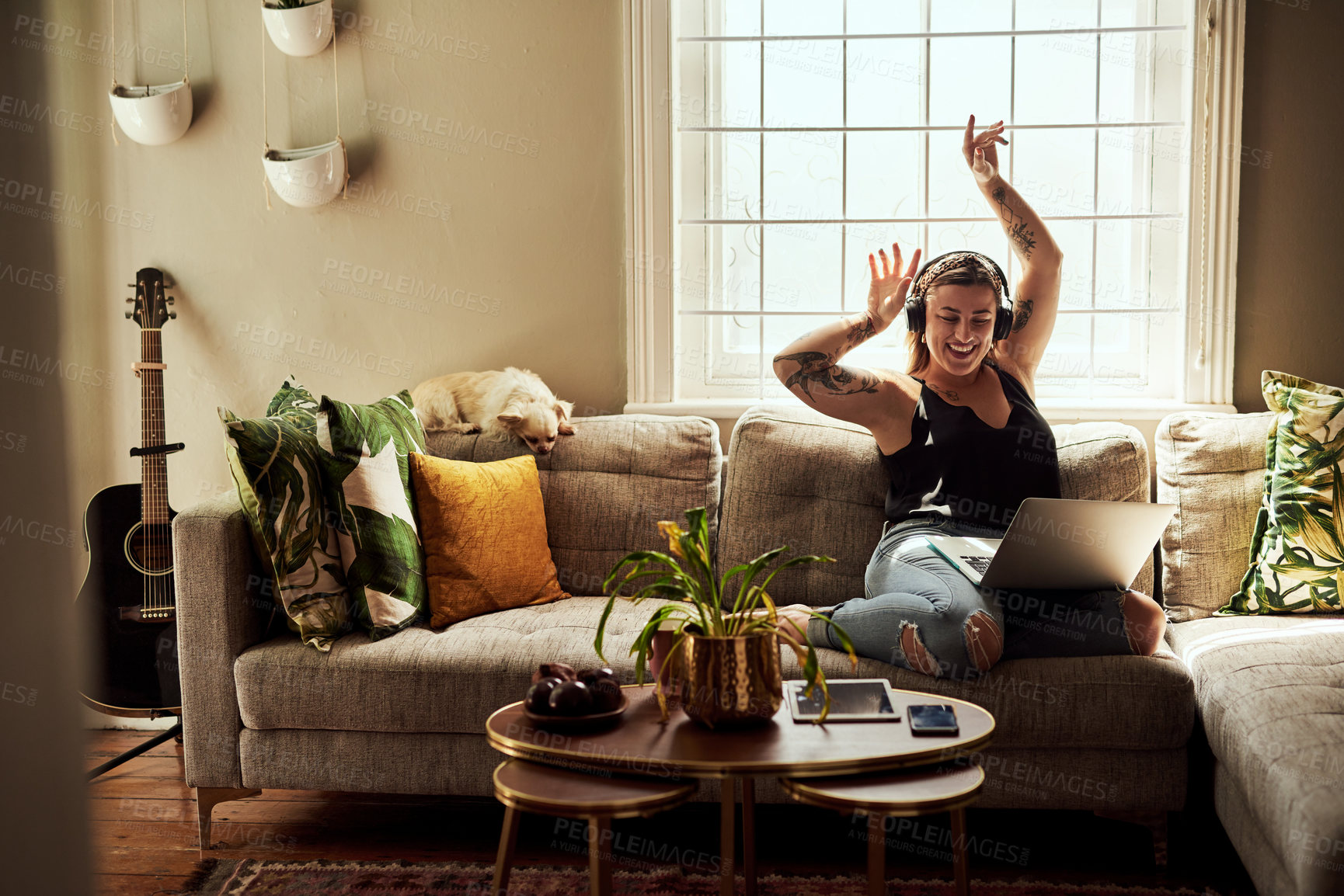 Buy stock photo Music, headphones and woman on sofa and laptop dancing, happy energy and mental health in boho apartment. Young person listening to audio technology, electronics and computer in living room or home