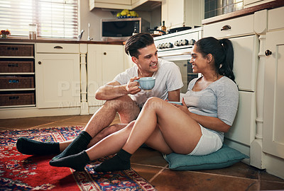 Buy stock photo Shot of a young couple having coffee in their kitchen at home