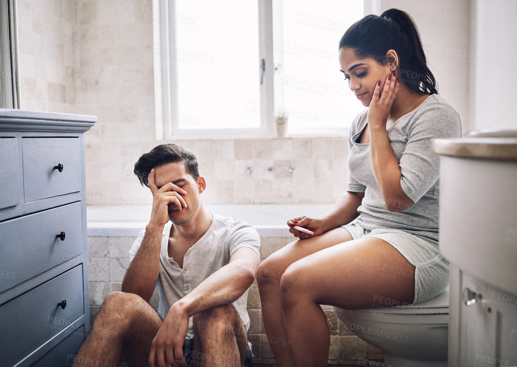 Buy stock photo Shot of a young couple looking upset after taking a home pregnancy test
