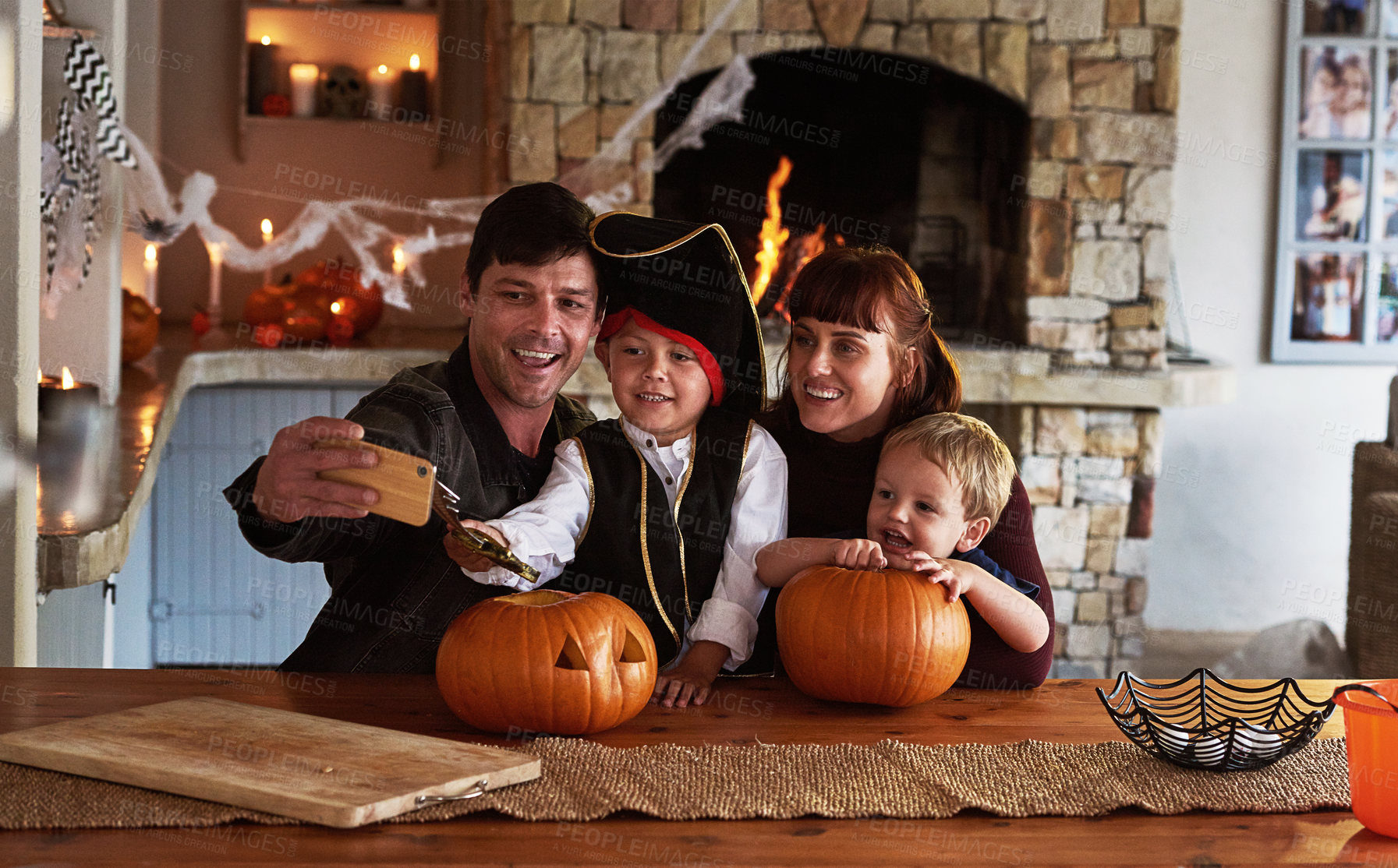 Buy stock photo Shot of an adorable young family taking selfies together with a cellphone on halloween at home