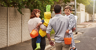 Buy stock photo Rearview shot of an adorable young family trick or treating together in the neighborhood on halloween