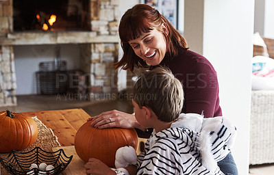 Buy stock photo Shot of a happy young mother carving out pumpkins and celebrating halloween with her young son at home