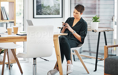 Buy stock photo Full length shot of an attractive young businesswoman sitting alone and texting on her cellphone in the office