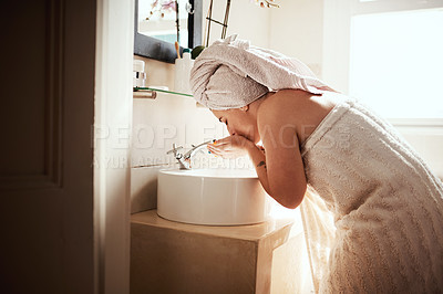 Buy stock photo Shot of a young woman washing her face during her morning beauty routine