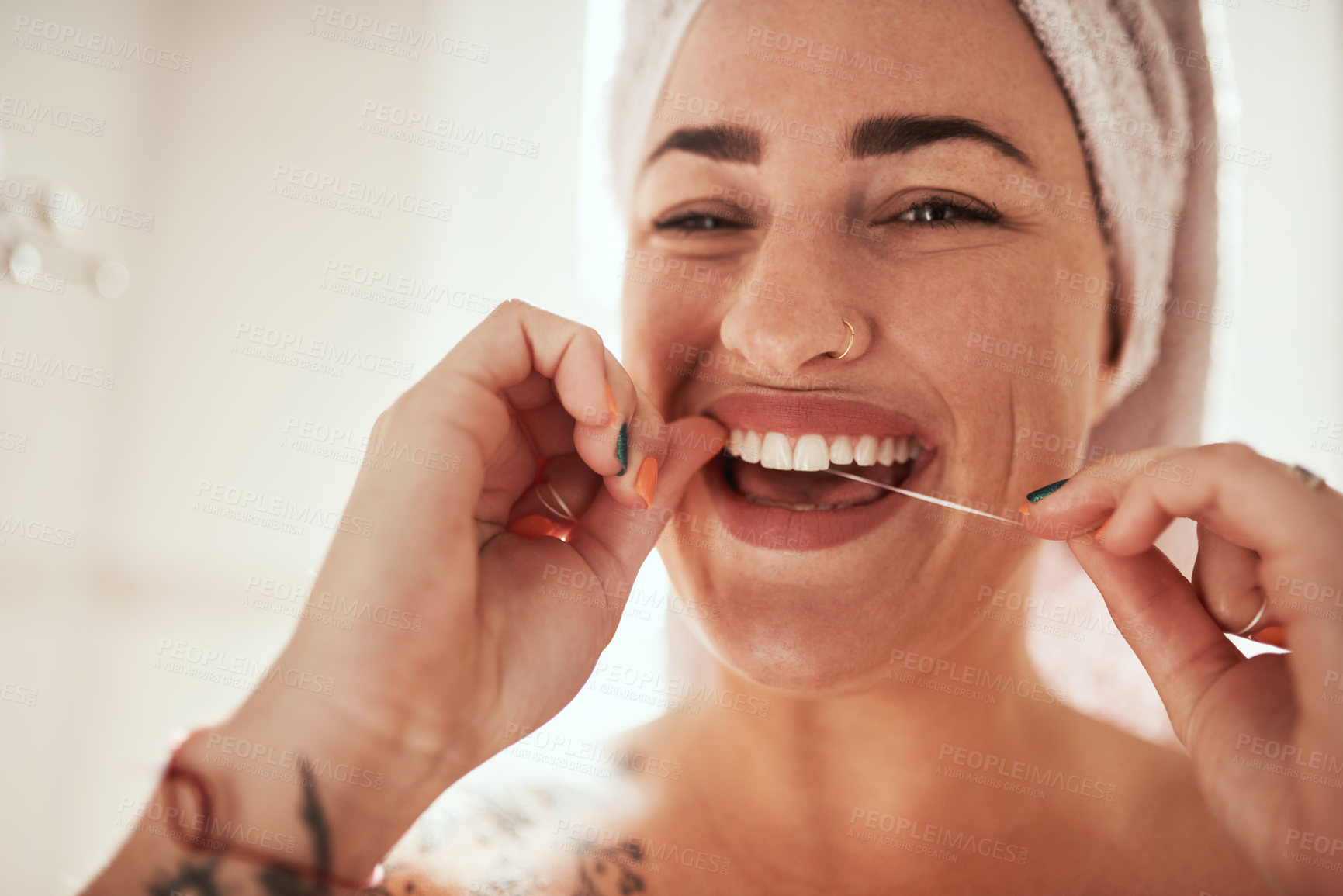 Buy stock photo Shot of an attractive young woman flossing her teeth in the bathroom at home