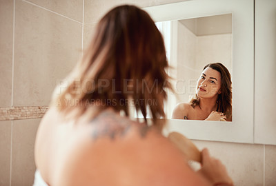 Buy stock photo Shot of an attractive young woman brushing her hair during her morning beauty routine at home