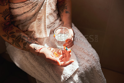 Buy stock photo Cropped shot of a woman taking a pill with a glass of water during her morning routine at home