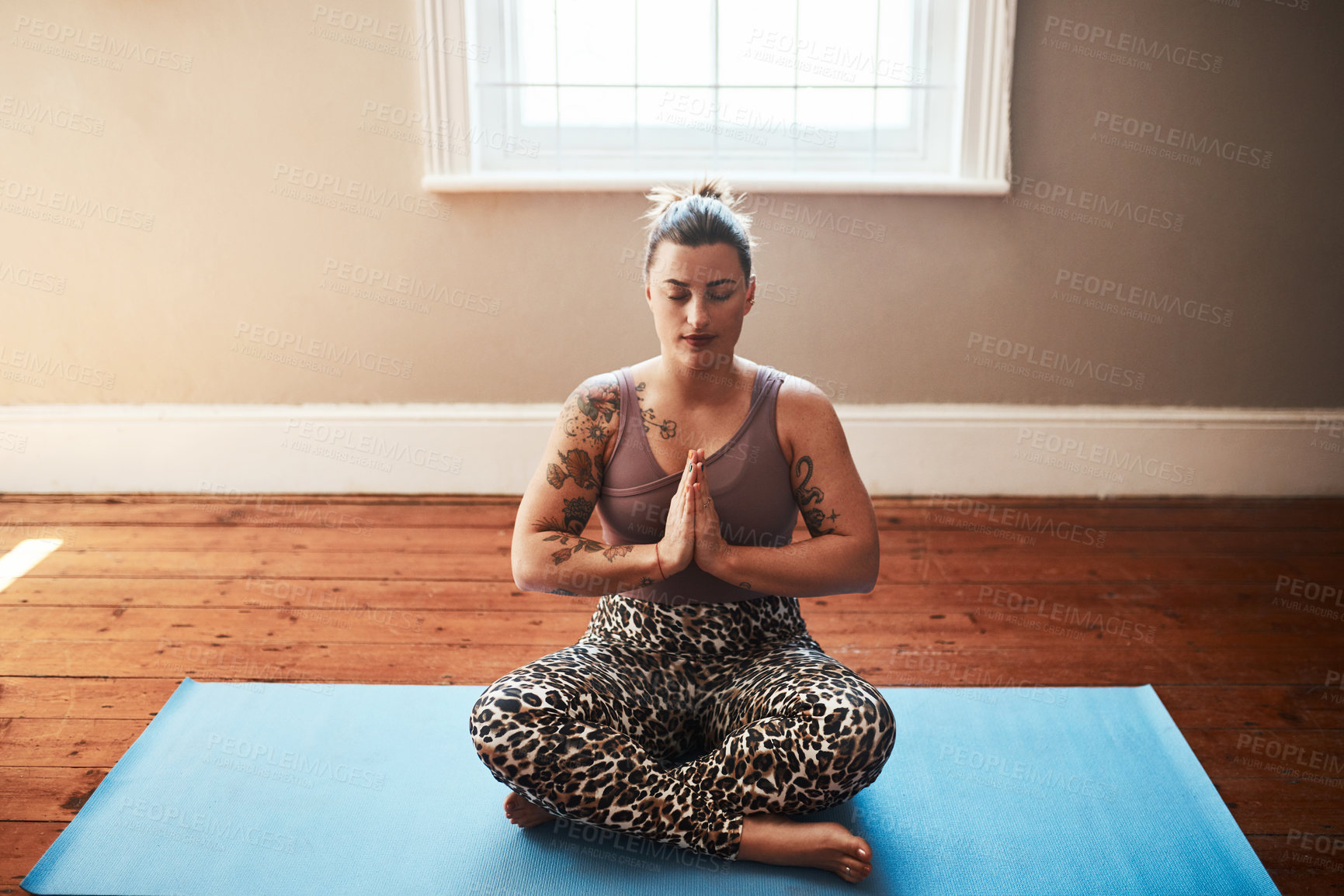 Buy stock photo Shot of a young woman meditating on a yoga mat at home