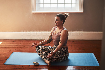 Buy stock photo Shot of a young woman burning a palo santo stick while sitting on a yoga mat at home