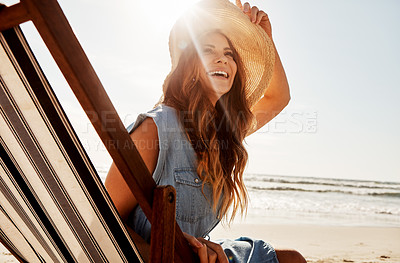 Buy stock photo Shot of a young woman relaxing on a lounger at the beach