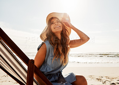 Buy stock photo Shot of a young woman relaxing on a lounger at the beach