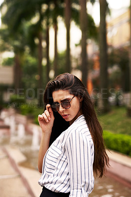 Buy stock photo Cropped shot of an attractive young woman looking back while walking down the street outdoors