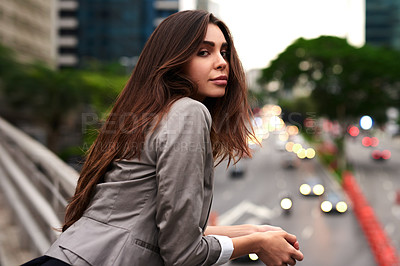 Buy stock photo Cropped portrait of an attractive young woman leaning against a balcony in the city during the day