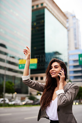 Buy stock photo Cropped shot of an attractive young businesswoman hailing for a taxi while taking a phonecall in the city during the day