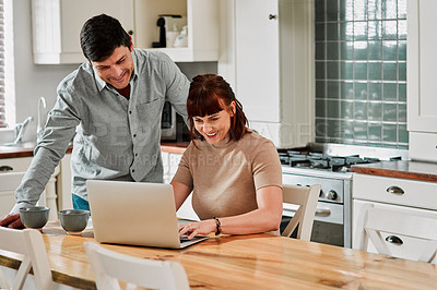Buy stock photo Shot of a woman using a laptop with her husband standing beside her