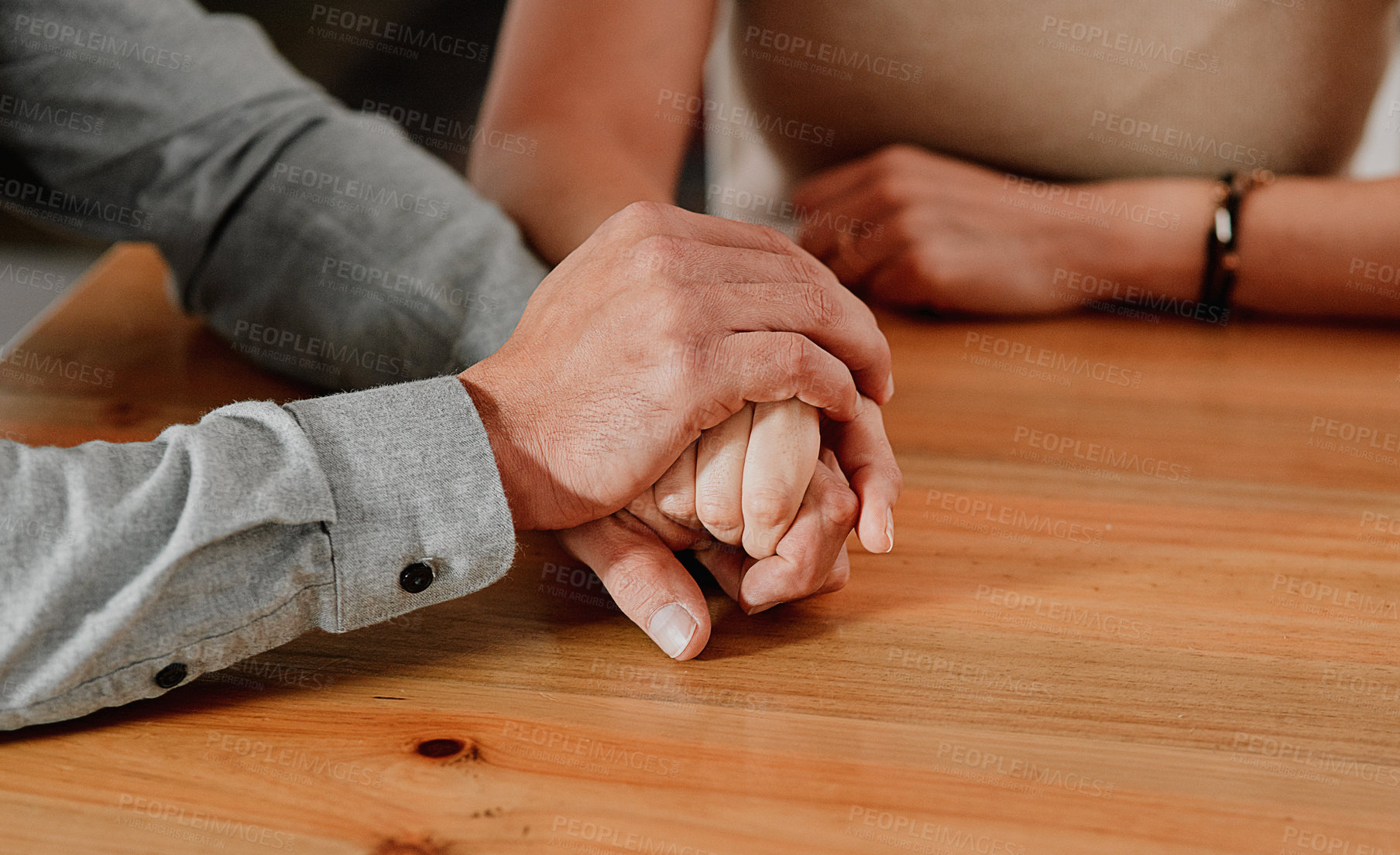 Buy stock photo Cropped shot of an unrecognizable couple holding hands on a wooden table