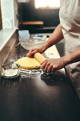 Buy stock photo Cropped shot of an unrecognizable woman flattening dough with a rolling pin while baking inside her kitchen at home