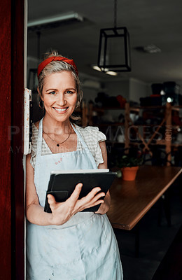 Buy stock photo Cropped portrait of an attractive mature woman standing alone and using a tablet in her pottery workshop